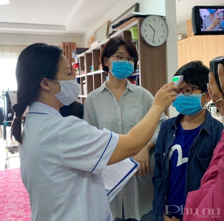 Cán bộ y tế phường Mễ Trì kiểm tra thân nhiệt cho người cách ly y tế tại nhà.