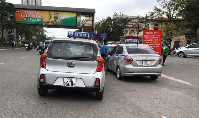 Taxi che biển số, đỗ tràn dưới lòng đường, trước cổng Bệnh viện Bạch Mai chèo kéo khách. Ảnh: Tiền Phong