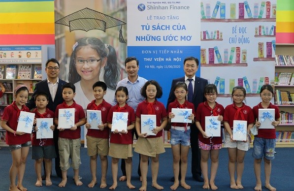 Ông Trần Văn Hà Giám đốc Thư viện Hà Nội và đại diện Ban Giám đốc Shinhan Finance trao quà cho các em học sinh