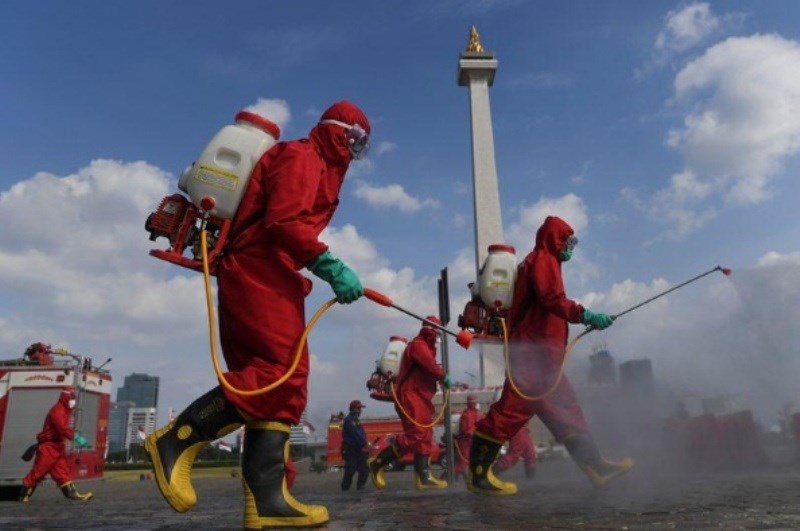Lính cứu hỏa mặc trang phục bảo vệ phun thuốc khử trùng tại khu vực Đài tưởng niệm quốc gia tại Jakarta, Indonesia.