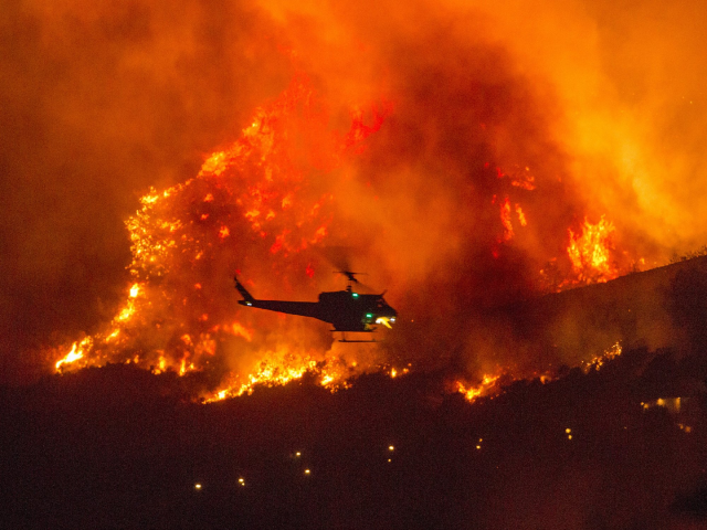 Một chiếc trực thăng chuẩn bị đổ nước xuống đám cháy