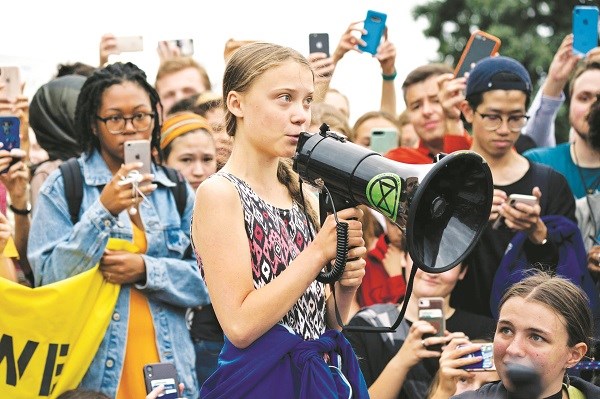Greta Thunberg cầm loa kêu gọi mọi người, chính phủ hành động để chống lại biến đổi khí hậu.