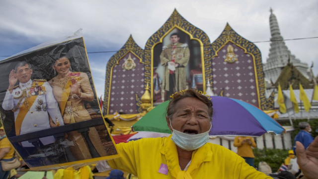 Những người ủng hộ chế độ quân chủ giơ cao hình ảnh của Vua Maha Vajiralongkorn và Hoàng hậu Suthida khi họ tập trung trước Grand Place ở Bangkok.