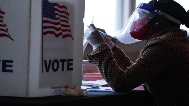 Nhân viên tại điểm bỏ phiếu hướng dẫn một cử tri trước khi bỏ phiếu bằng lá phiếu giấy vào Ngày Bầu cử ở Atlanta. (Ảnh AP / Brynn Anderson).