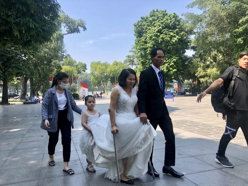 Cô bé Nguyễn An Nhiên đỡ váy cưới cho mẹ để bố mẹ tiến vào tượng đài Lý Thái Tổ và chụp ảnh cưới