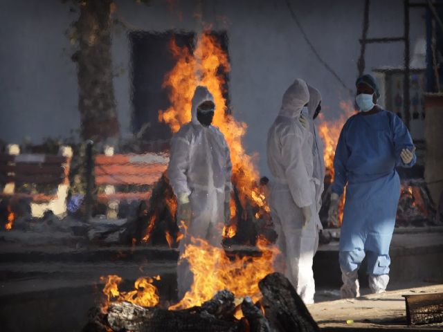 Nhân viên y tế và người thân đứng bên giàn hỏa táng một nạn nhân COVID-19 ở New Delhi, Ấn Độ.