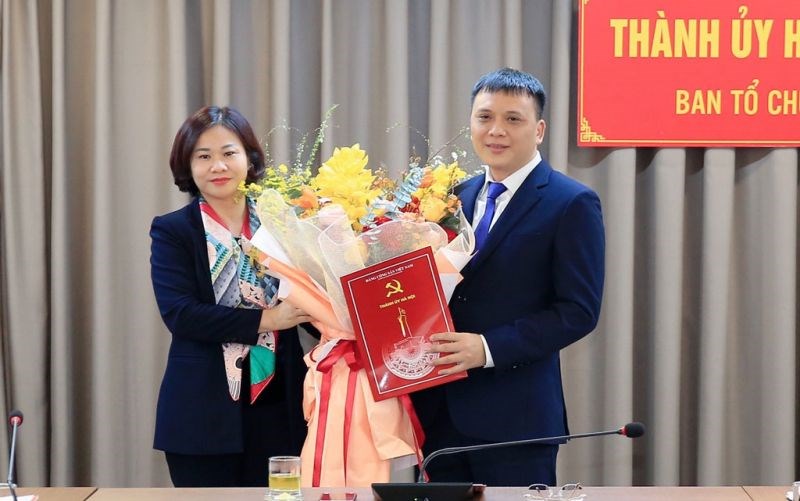 Phó Bí thư Thường trực Thành ủy Hà Nội Nguyễn Thị Tuyến trao quyết định của Ban Thường vụ Thành ủy và tặng hoa chúc mừng đồng chí Nguyễn Minh Long.