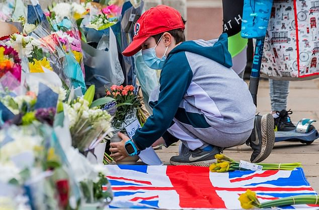Một cậu bé cầm chậu hoa đặt bên ngoài Cung điện Buckingham sau khi Hoàng thân Philip qua đời.