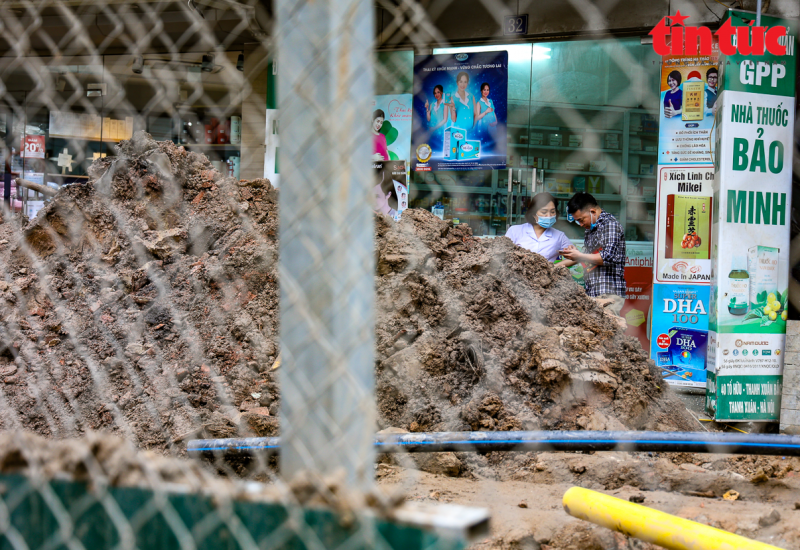 Đất đá từ quá trình thi công cống thoát nước của dự án hầm chui Lê Văn Lương chất đống trên vỉa hè đường Tố Hữu, gây ảnh hưởng đến các hộ kinh doanh.
