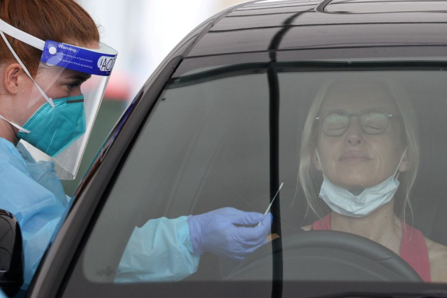Nhân viên y tế lấy mẫu xét nghiệm cho một người dân tại trung tâm xét nghiệm COVID-19 ở Bãi biển Bondi, Úc.