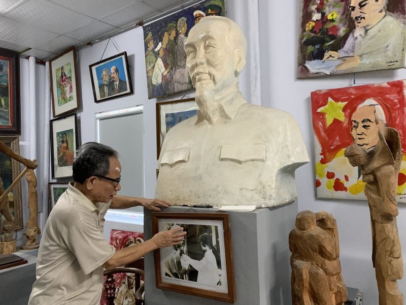 Họa sỹ Lê Duy Ứng bên bức tranh vẽ Bác Hồ bằng máu treo trong bảo tàng riêng của nhà mình