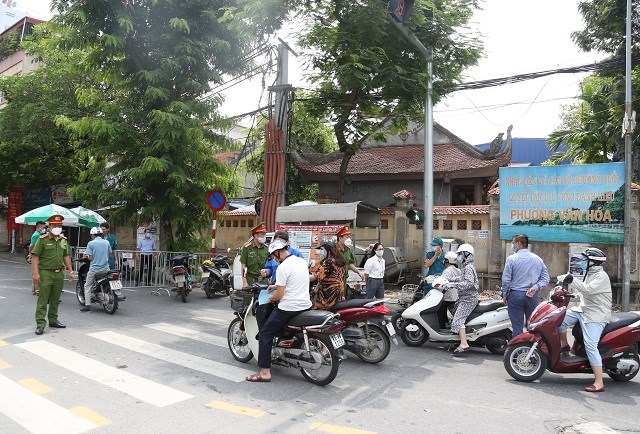 Lực lượng chức năng kiểm tra giấy đi đường tại chốt kiểm dịch Covid-19 trên phố Lạc Long Quân. Ảnh: Thanh Hải