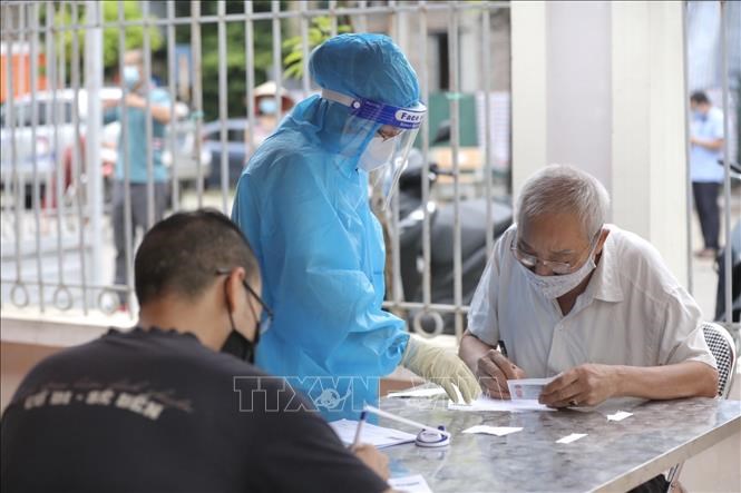 Nhân viên y tế hướng dẫn người dân khai báo y tế khi đến lấy mẫu xét nghiệm COVID-19 tại điểm lấy mẫu tập trung xã Ngũ Hiệp (ảnh chụp ngày 10/8/2021).