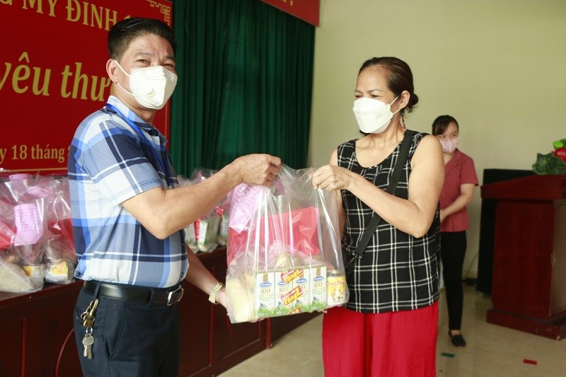 Đồng chí Trịnh Văn Quế, Chủ tịch UBND phường Mỹ Đình I trao quà hỗ trợ trẻ em bị ảnh hưởng bởi dịch qua người thân của trẻ.