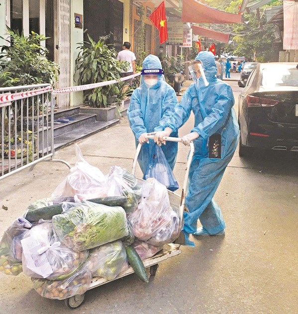 Các chị em phụ nữ phường Thanh Xuân Trung mặc đồ bảo hộ, đi chợ hộ và đưa đồ ăn cho các hộ dân trong thời gian cách ly tại phường (Ảnh: Hồng Nhung)