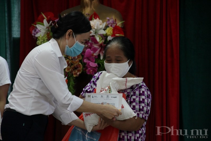 Chị Nguyễn Hoàng Yến, phụ trách dự án của Viện LIGHT trao quà cho một phụ nữ di cư có hoàn cảnh khó khăn của quận Ba Đình.