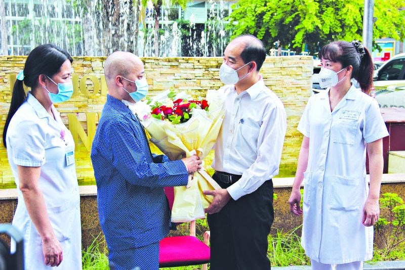 Đại diện lãnh đạo Sở Y tế, bệnh viện Đa khoa Thanh Nhàn tặng hoa chúc mừng anh Hoàng Văn Ngọc điều trị khỏi Covid-19 và được xuất viện.