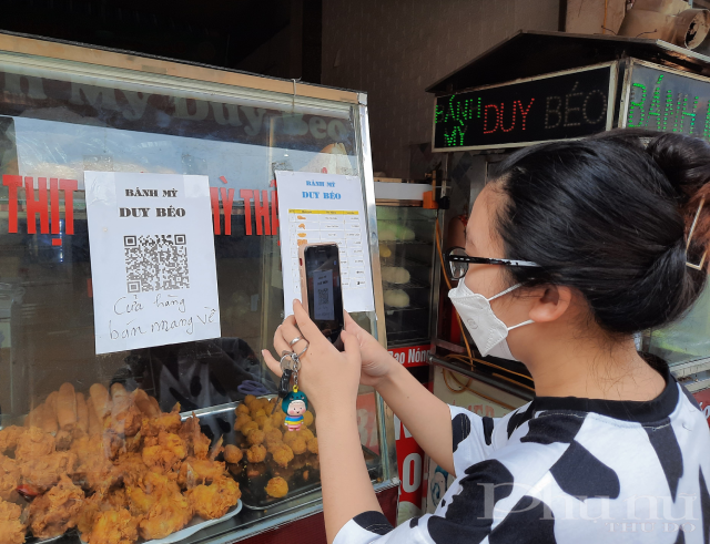 Một khách hàng đang thực hiện quét QR khai báo Y tế tại cửa hàng của cô Bằng.