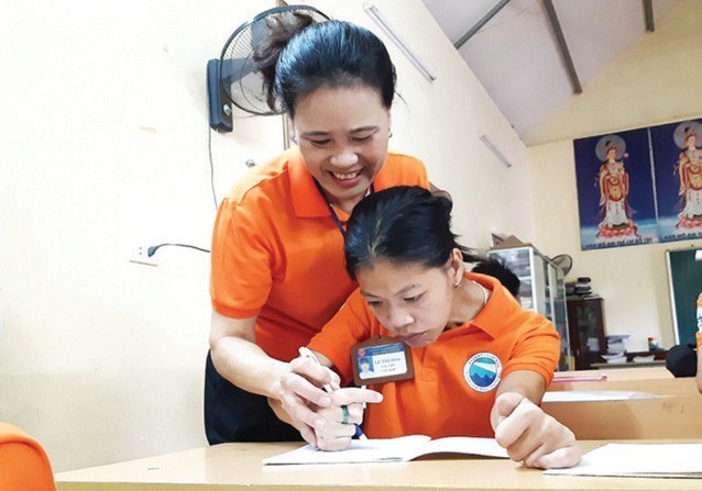 Cô giáo Lê Thị Hòa hướng dẫn học sinh khuyết tật làm bài.