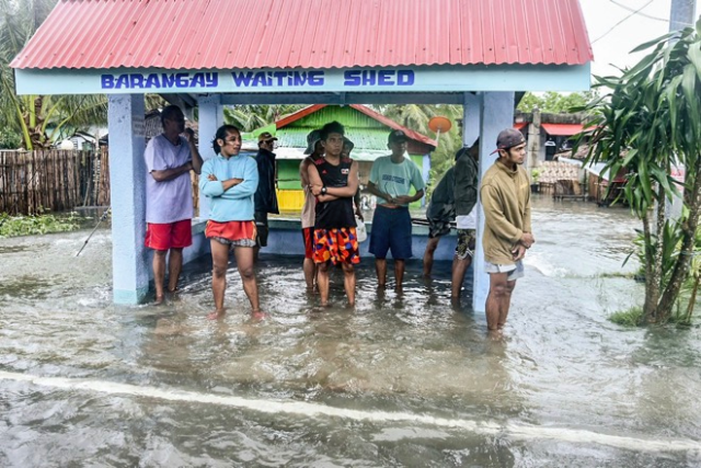 Cư dân địa phương đứng trú chân tại một điểm ngập lụt do ảnh hưởng của siêu bão.
