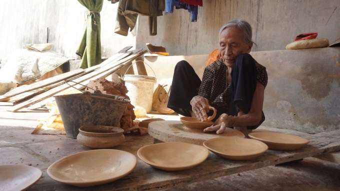 Một cụ bà ở làng Trù Sơn ngồi tì miết tạo hình nồi đất.