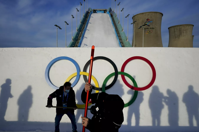 Hai công nhân chuẩn bị cầu nhảy cho buổi tập của các vận động viên trước cuộc thi trượt tuyết tự do.