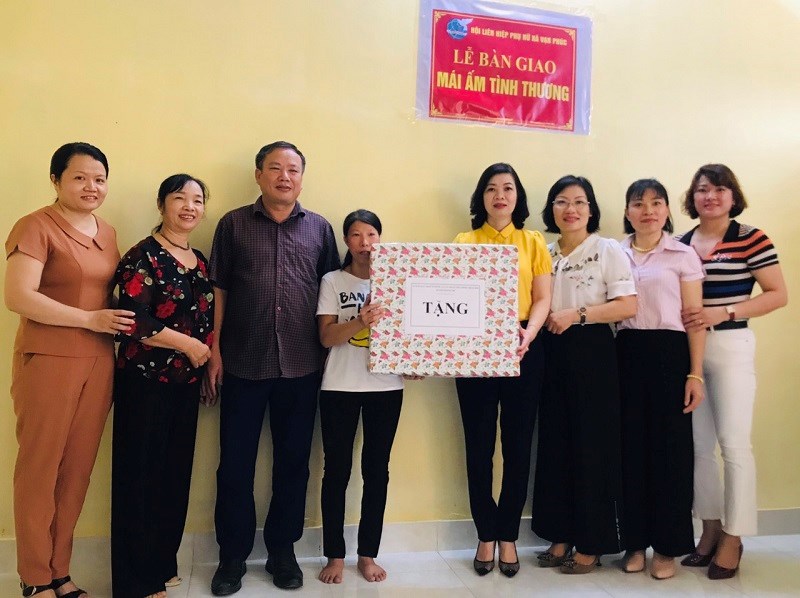 Đồng chí Trần Thị Vân - Huyện ủy viên - Chủ tịch Hội LHPN huyện ( thứ 4 từ phải sang)tặng quà hội viên phụ nữ Phạm Thị Mão